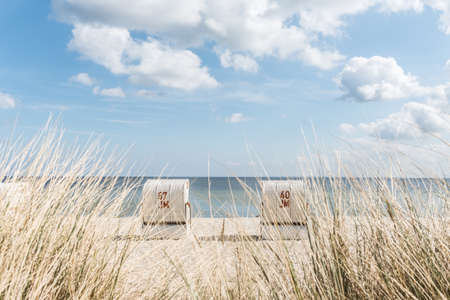 Two baltic sea beach chairs at famous holiday an camping area Scharbeutz having clear blue sky with white clouds.